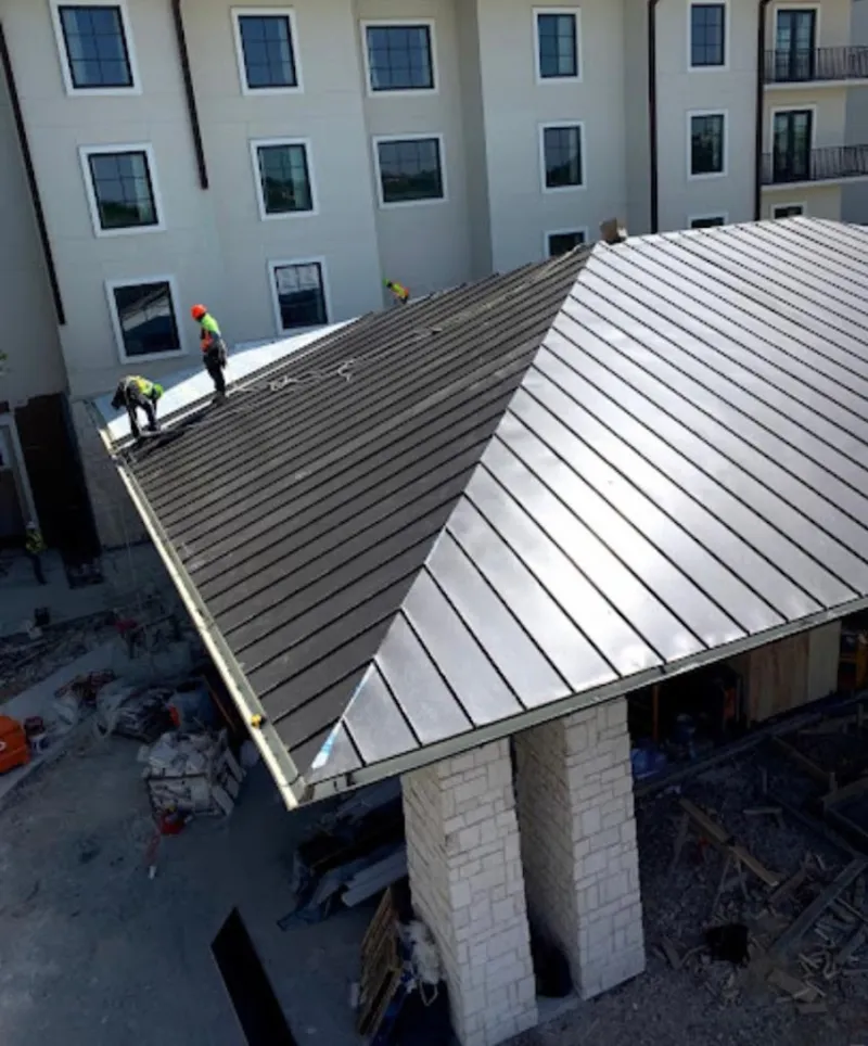 Crew installing standing seam metal roof panels on a commercial project in Alamosa